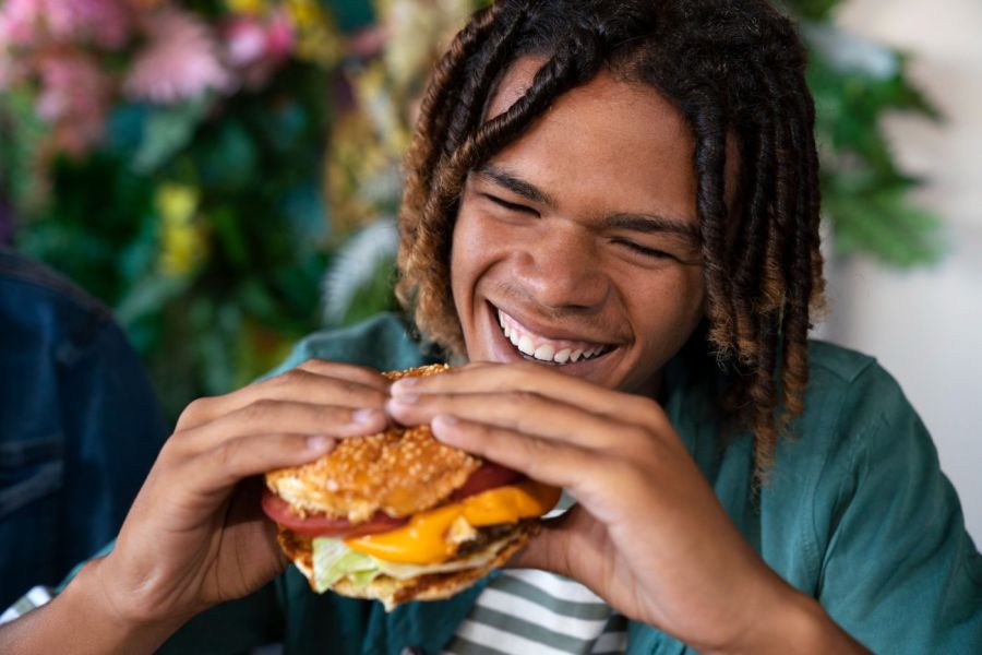 Viridian Central A man with dreadlocks enjoying a hamburger.