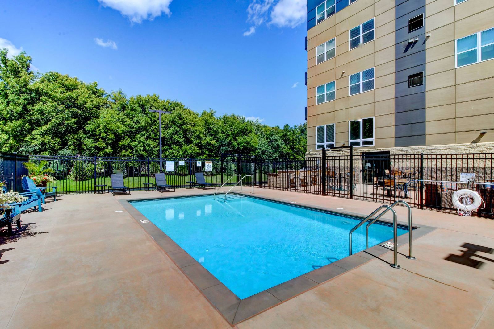 The pool at Viridian Central apartment complex on a sunny day, surrounded by lounge chairs and umbrellas.