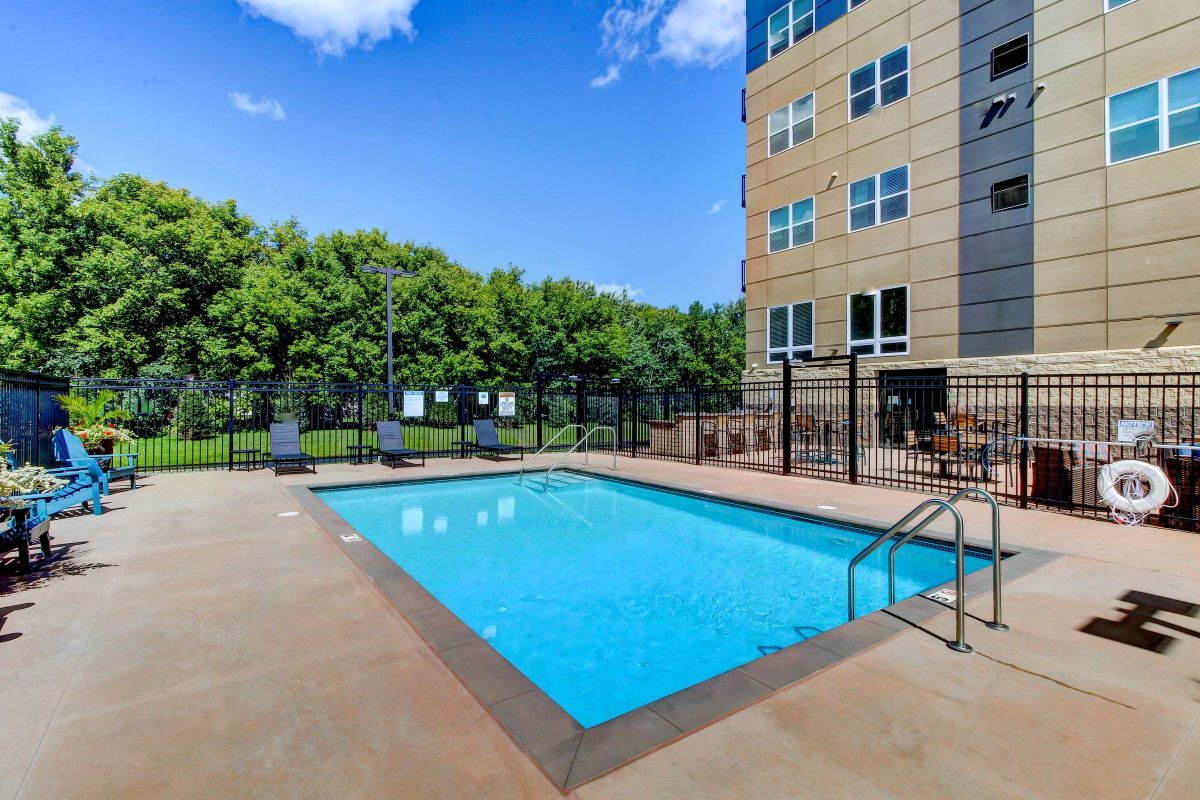 Viridian Central Outdoor pool surrounded by lounge chairs and umbrellas at Denver apartment complex.