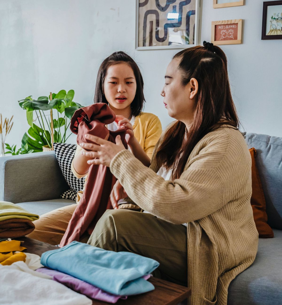 Viridian Central Two women sitting on a couch with clothes on the table in a cozy living room setting.
