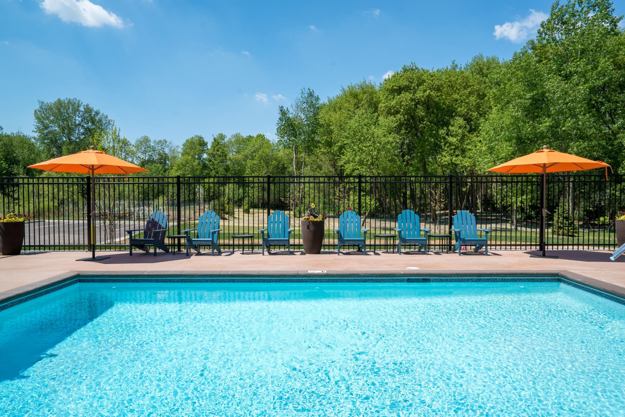 Viridian Central Poolside scene with blue chairs and orange umbrellas, inviting relaxation and enjoyment under the sun.